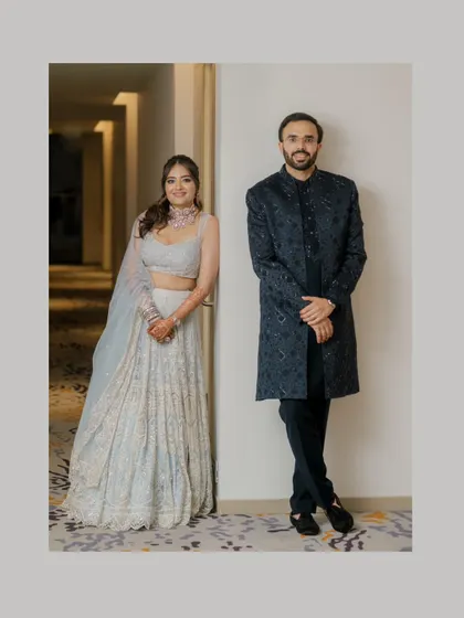 A stylish, full-length portrait of the couple in their elegant reception outfits, showcasing their modern aesthetic.