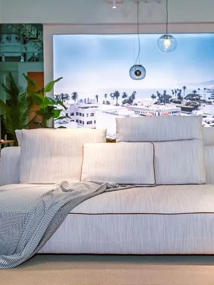 The Montserrat Sofa, styled with a soft throw, demonstrates its generous proportions and inviting comfort. This modular piece can be configured to fit any living room, making it a versatile foundation for a luxurious and relaxing home environment.