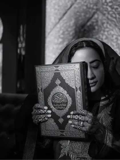 A black and white portrait of the bride holding the Quran, a moment of quiet reverence and faith.