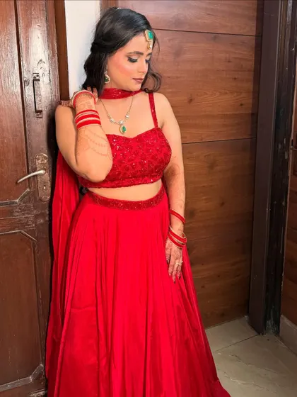 A stunning party look in a simple red lehenga, elevated by bold makeup and statement jewelry.