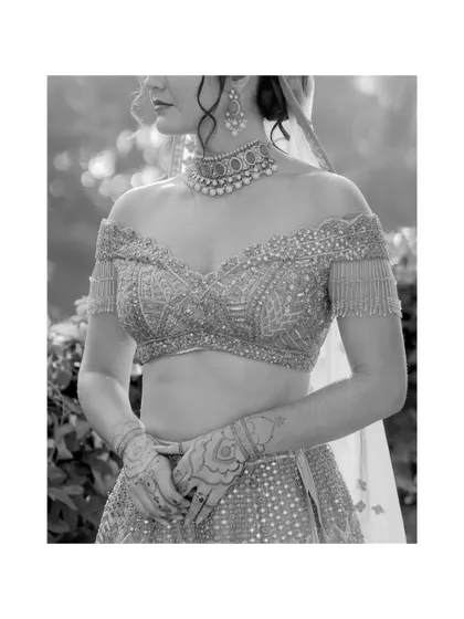 A detailed black and white shot of the bride's off-the-shoulder blouse and intricate henna. This portrait focuses on the beautiful craftsmanship of her wedding look.