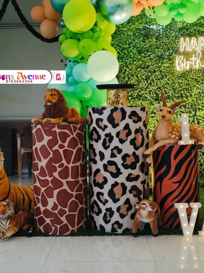 A closer view of the animal-themed cake stands and props. The pedestals are wrapped in giraffe, leopard, and tiger prints, perfectly matching the safari party concept.