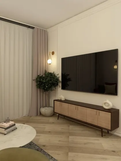 The TV wall in this apartment living room is kept simple with a minimalist media console and elegant wall sconces, allowing the space to feel uncluttered.
