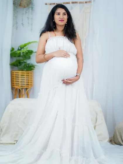 A full view of the flowing white gown for this maternity shoot. The simple makeup and hair allow the beauty of the moment and the dress to take center stage.