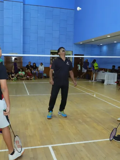 An adult player serves during a doubles match, highlighting the competitive spirit in our adult batches.