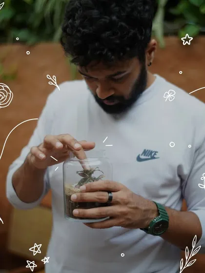 A guest puts the finishing touches on his terrarium, ensuring every plant and stone is perfectly placed. The process is one of focus, creativity, and connection with nature.