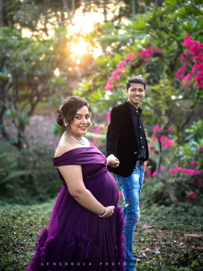 A lovely "follow me" style shot, inviting the viewer into their story. The soft sunlight filtering through the trees adds a touch of magic to this outdoor maternity photo.