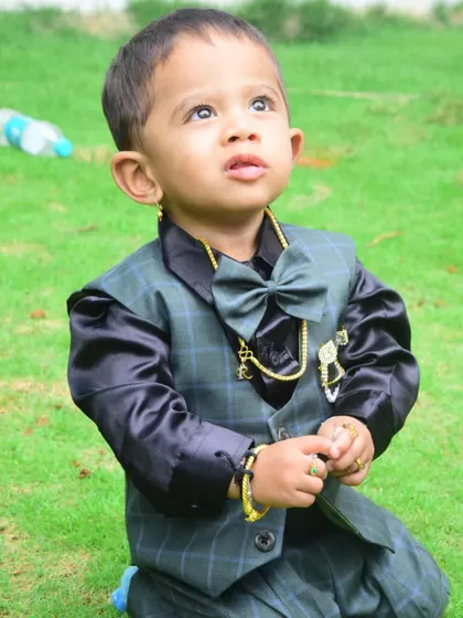 Looking up with his innocent eyes. This little boy's custom suit is both stylish and comfortable for him to play in.