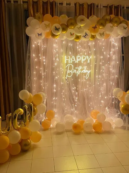 A beautiful birthday setup with a fairy light and curtain backdrop, personalized with the name "Ruchi" in foil letters.