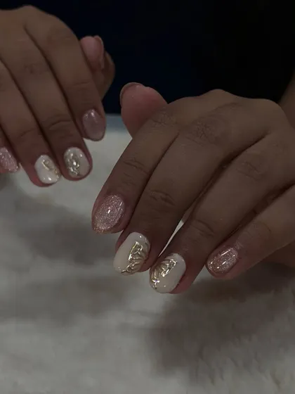 A perfect summer look. These nails feature a soft glitter base with delicate gold butterfly accents, a simple yet elegant design.