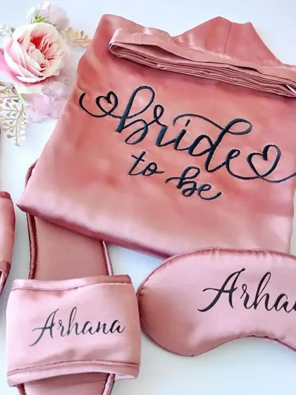 A beautiful "Bride to be" satin robe, personalized with her name, and paired with matching slippers and an eye mask. The perfect outfit for getting ready on the big day.