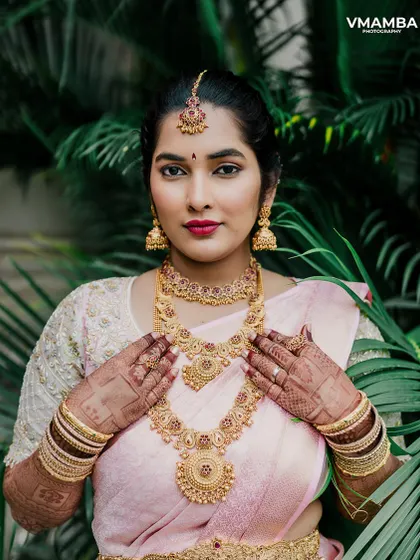 An elegant bridal portrait, showcasing the bride's intricate gold jewelry and beautiful pink saree.