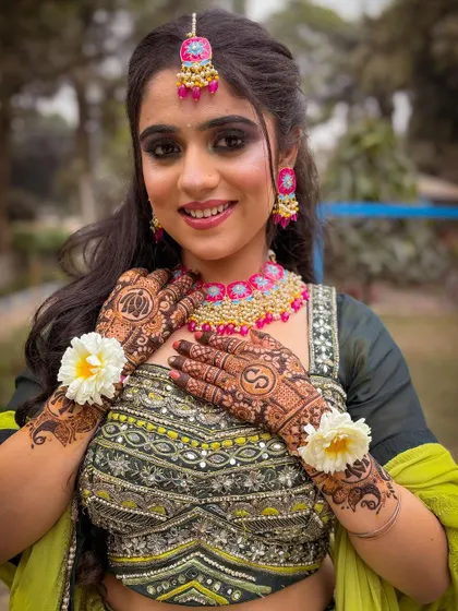 A happy bride-to-be showing off her complete Mehendi look. The green and pink color combination is a classic choice.