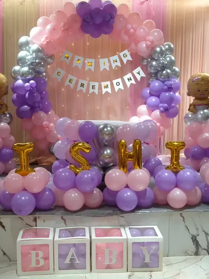 The complete stage decor for a naming ceremony, including a balloon ring, balloon pillars with baby toppers, and the baby's name spelled out.