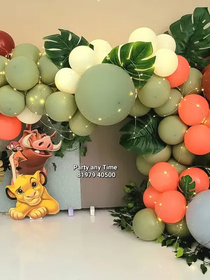 A simple and sweet cake smash decoration featuring a Lion King theme with a Simba cutout and a balloon garland in jungle colors.