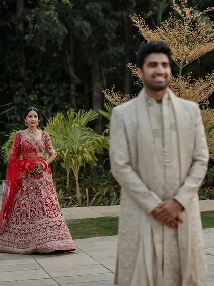 A regal portrait of the couple in their stunning red and cream wedding attire. We use architectural elements like staircases to add a touch of grandeur to our compositions.