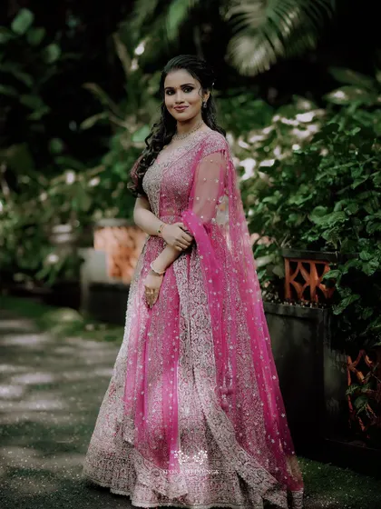 A full-length portrait of the bride-to-be, her sparkling pink lehenga shining in the light.