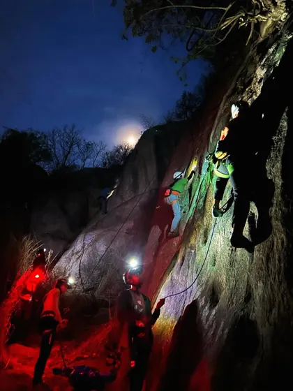 A vibrant scene from a night climb, with red and white headlamps lighting up the rock face. It's a surreal and exciting way to experience the sport.