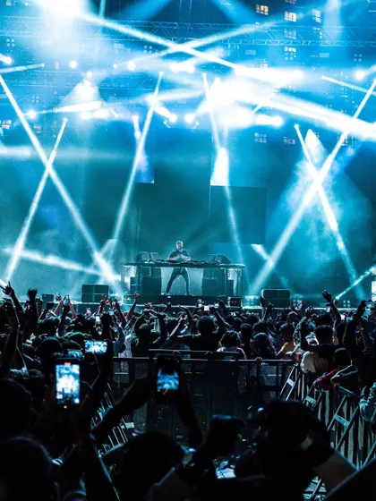A stunning shot of the stage bathed in blue light, with the crowd reaching for the DJ.
