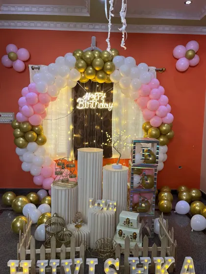 A beautiful pink, white, and gold themed birthday setup for a home celebration, complete with a full set of props.