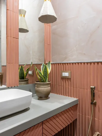 Another view of the terracotta and marble powder room, highlighting the interplay of textures. The vertical fluting of the tiles contrasts beautifully with the smooth marble and the organic shape of the snake plant.