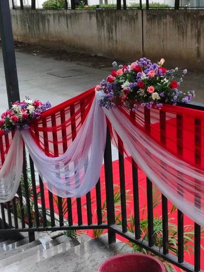 Railing decoration for a corporate event, using red and white drapes with flower bouquets.