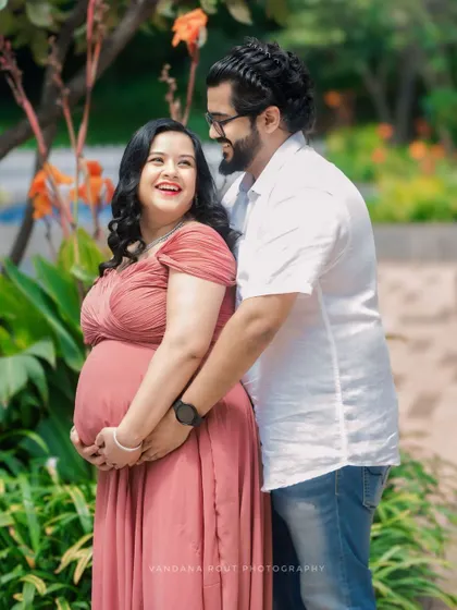 A candid, happy moment between a couple during their outdoor maternity session. The natural greenery and soft lighting highlight their joyful anticipation.