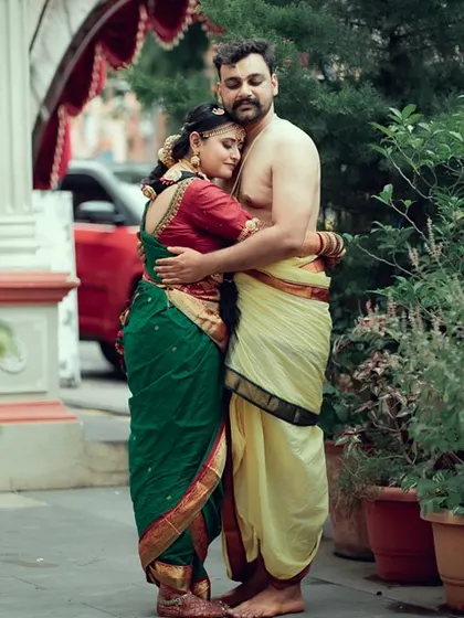 A tender embrace between a couple in traditional South Indian wedding attire, captured in a quiet outdoor moment.