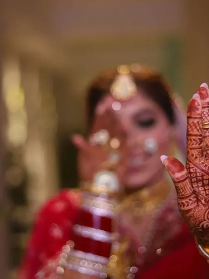 An artistic bridal shot with a focus on the mehendi-adorned hand, creating a sense of mystery and anticipation.