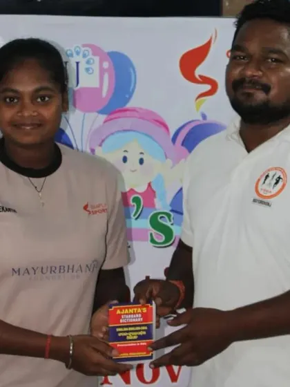 A young athlete receives a prize for her participation in the Children's Day competitions. Recognizing effort and participation encourages all children to get involved.