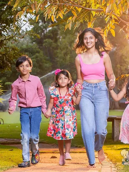 A beautiful moment of four siblings walking hand-in-hand through a park. This photo captures the fun and energy of a big family enjoying time together outdoors.