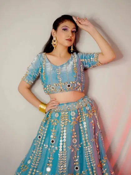 This full-length shot shows the beautiful A-line silhouette and the sparkling mirror work of the blue lehenga.