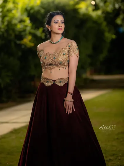 This full-length portrait showcases the beautiful flow of the velvet lehenga skirt. The natural outdoor setting provides a lovely contrast to the formal attire.