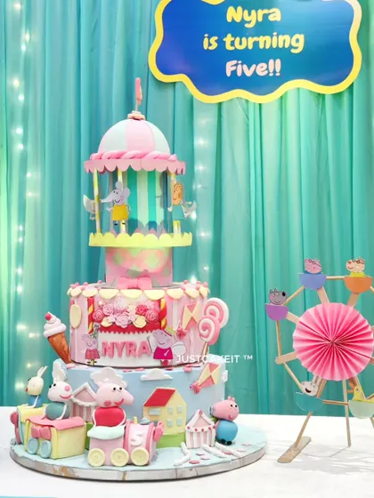 Another view of the magnificent Peppa Pig party cake, set up at the event. The multi-tiered design includes a train, a ferris wheel, and a carousel, creating an entire Peppa-themed amusement park.