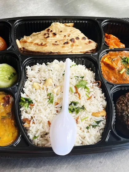 Rice, folded bread, curries, salad and a sweet fill the separate compartments of this Indian meal tray we pack.