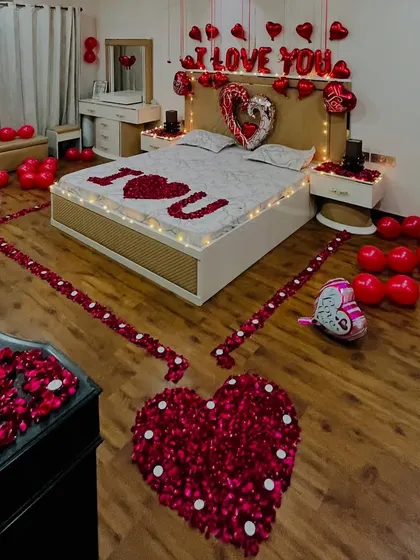 This high-angle shot captures the complete layout of our romantic room setup, including the petal-lined path, the decorated bed, and the placement of balloons throughout the room for a full immersive effect.