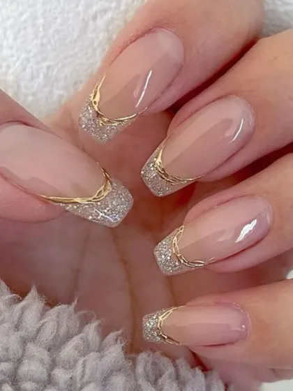 A glamorous take on the French manicure with a square shape and a sparkling silver glitter tip outlined in gold.