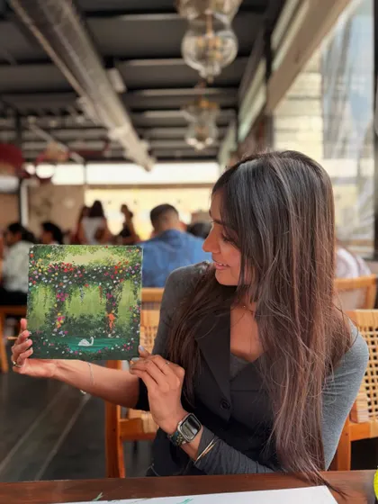 Me holding my finished swan in a flower garden painting. I'm so proud of how all the tiny, colorful flowers came together to create this lush scene.