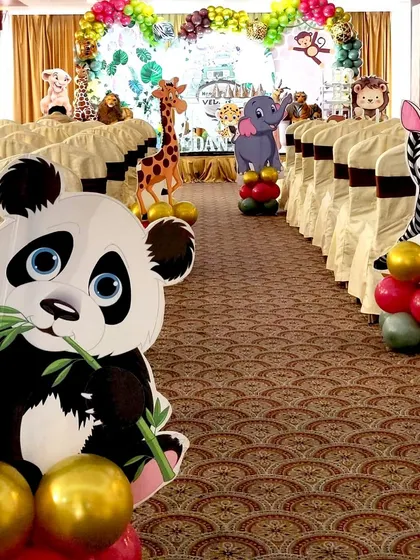 I make sure the theme extends beyond the main stage. Here, the party entrance aisle is lined with large cutouts of jungle animals like a panda, zebra, and giraffe, each with a small balloon cluster to welcome guests into the wild.