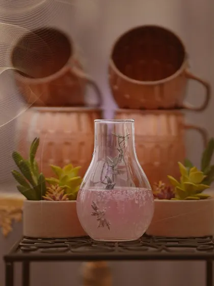 We create signature beverages to match the theme of your event. This image showcases a beautifully presented pink cocktail in a unique flask, surrounded by succulents.