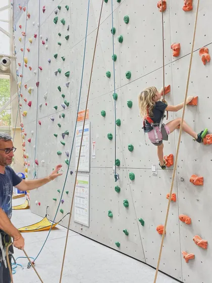 A father carefully belays his daughter as she climbs. We love seeing families climb together, sharing the experience and supporting each other every step of the way.