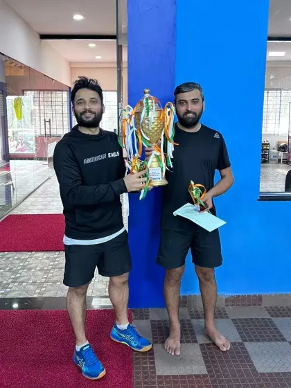 The winners of the adult men's doubles tournament holding their impressive championship trophy.