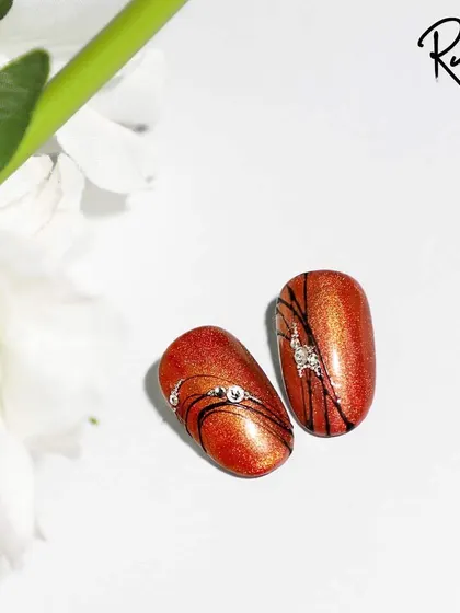 A simple yet striking design using spider gel to create fine lines over a metallic red base, finished with a few carefully placed crystals.