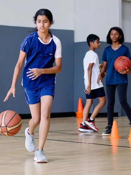 A young girl confidently dribbling through cones during a summer camp drill.