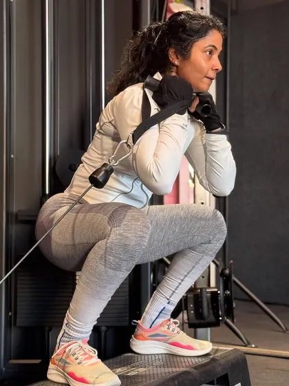 Using a cable machine for squats adds constant tension and helps reinforce proper form. This client is performing a cable-assisted squat on a step, which increases the range of motion and targets the glutes more effectively.