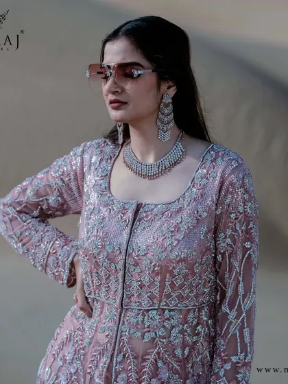 Soothing, subtle, and stunning. This classic double layer peach Indo-western gown is crafted beautifully in net fabric with detailed embellishments.