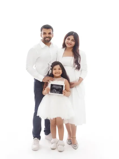 A classic family maternity photo, with the expecting mother, father, and their daughter posing together with the sonogram picture.