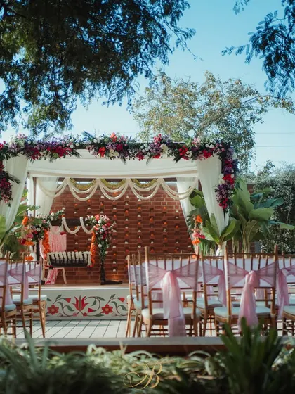 A wider perspective of the naming ceremony stage, showing the guest seating with pink chair ties that complement the floral arrangements. The design creates a festive and welcoming atmosphere.
