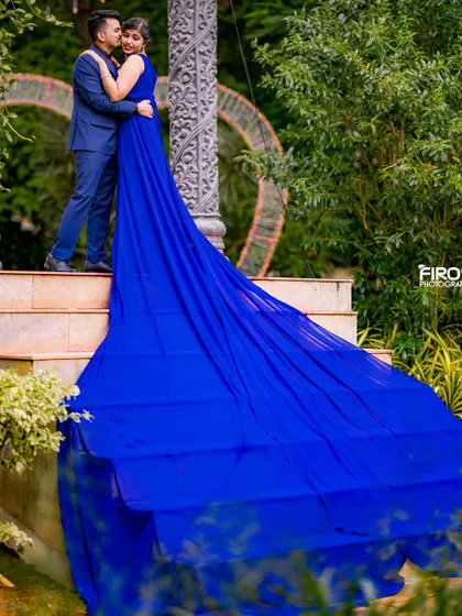 An intimate moment on the steps, captured from a distance. The long blue train of the gown is the centerpiece of this dramatic and romantic pre-wedding photograph.