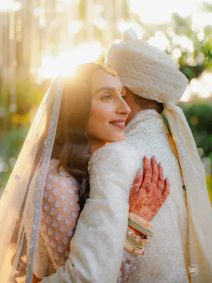 A bride's radiant smile, bathed in the warm glow of the setting sun. This beautiful candid moment from a wedding at Gallops, Mumbai, is filled with love, light, and happiness.